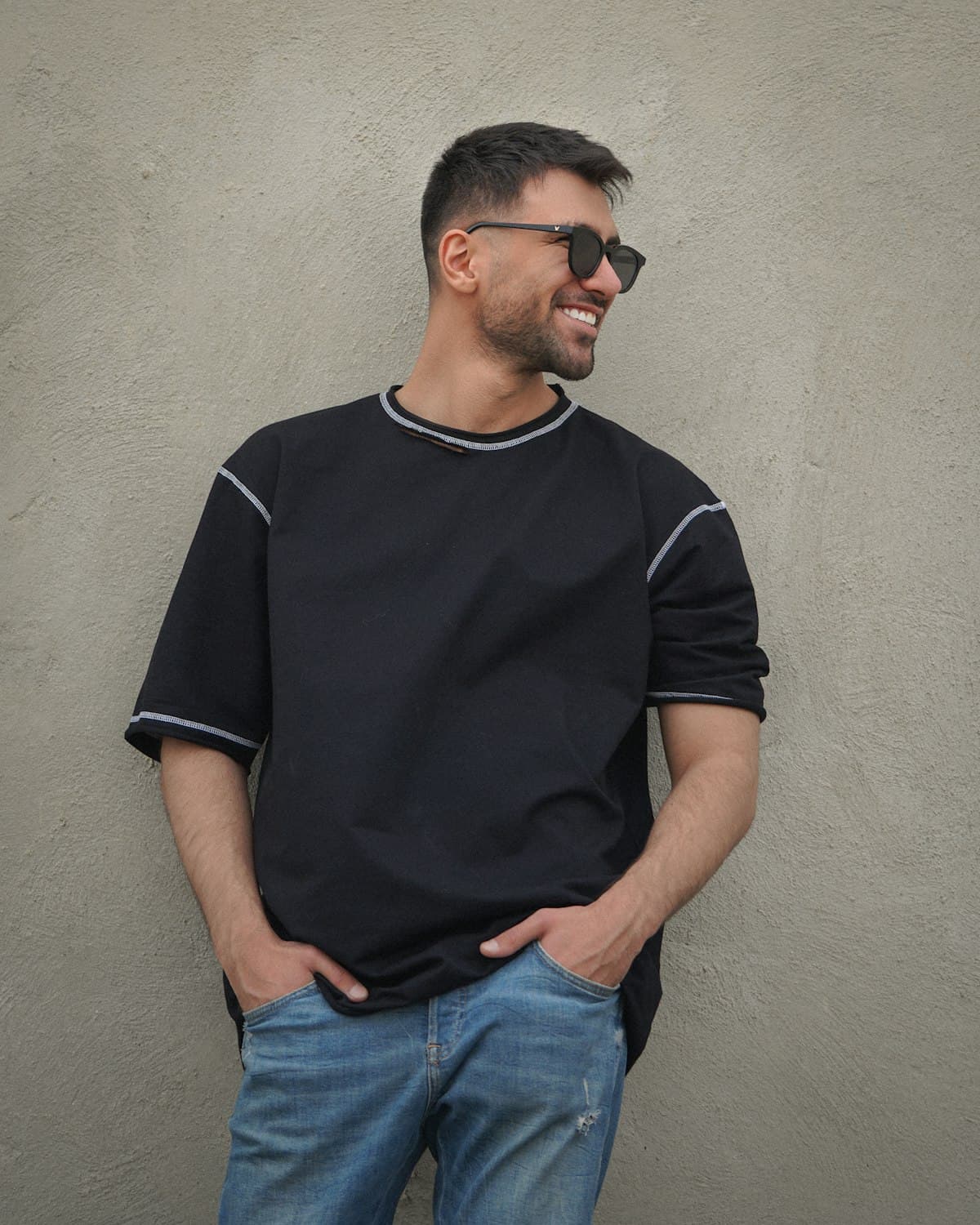 Homem sorrindo vestindo camiseta preta com frisos